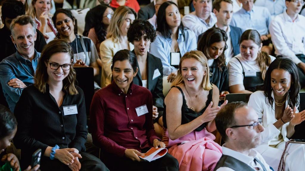 A group of people at a conference smiling and applauding.