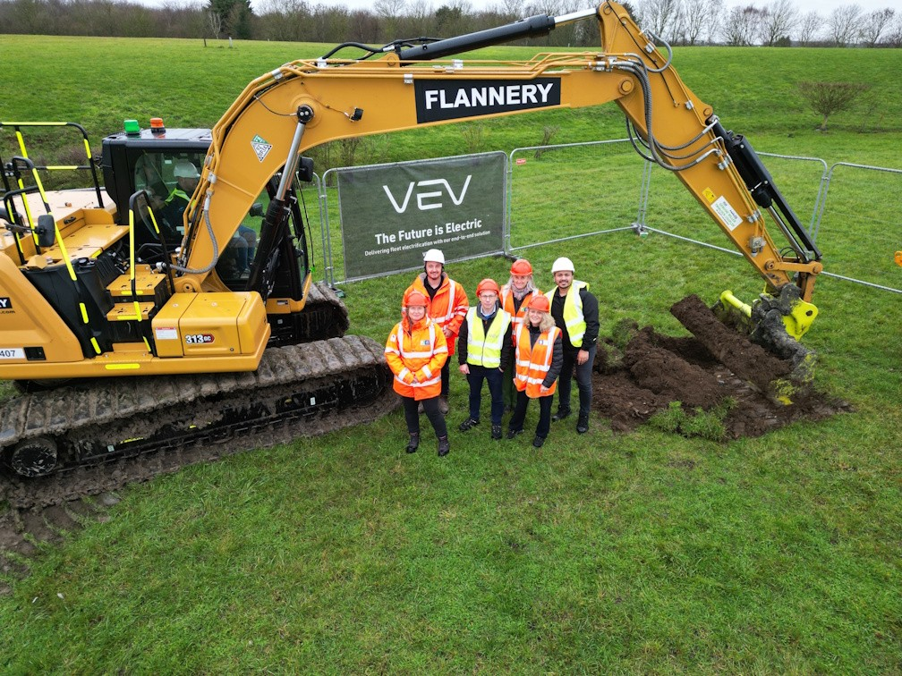 people standing next to a digger 