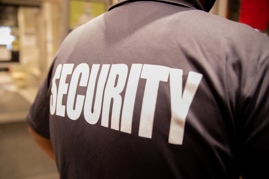 A close up rear view of a security guard's shirt with the word security across his back