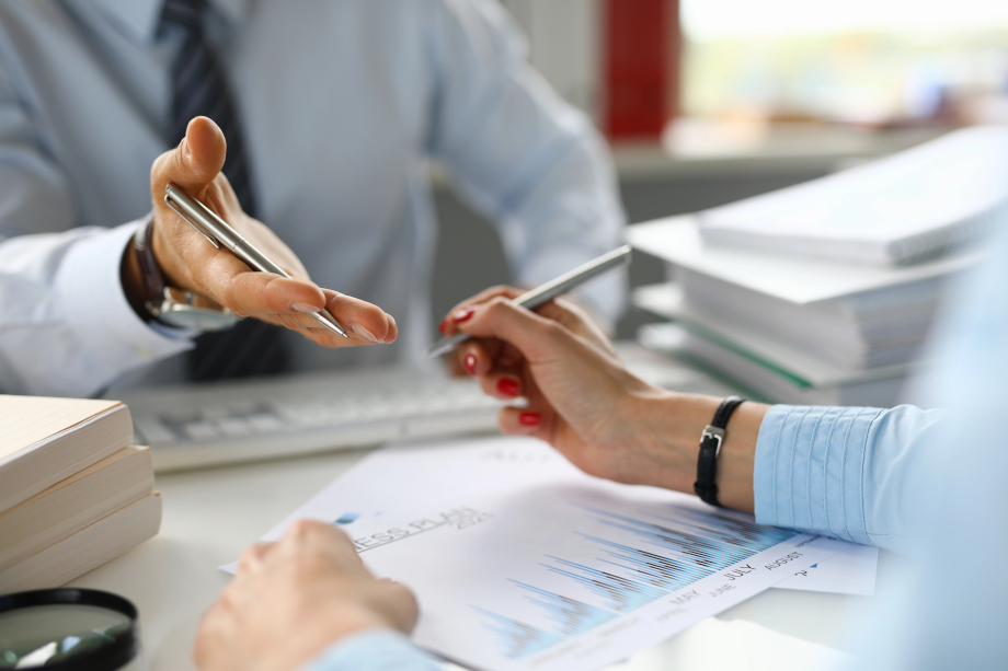 Close up of female and male hands holding pens, reviewing reports and forming a business plan 