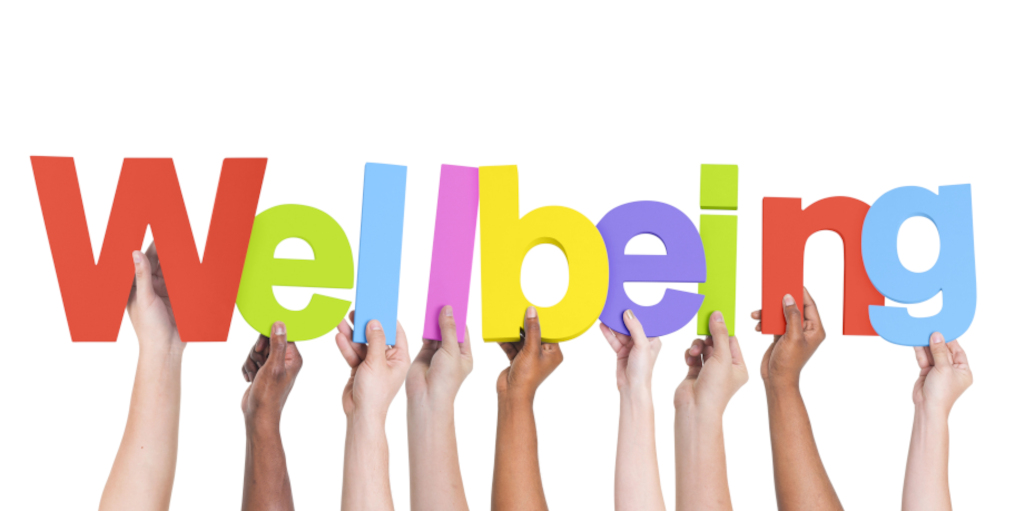 Hands holding up the multi coloured letters of the word 'wellbeing' 