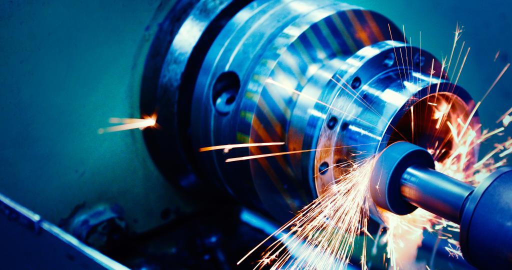 The image is washed in blue and hot white sparks fly off of a cylindrical saw as it comes into contact with metal.