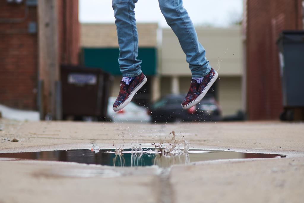 A pair of feet jumping from a puddle.