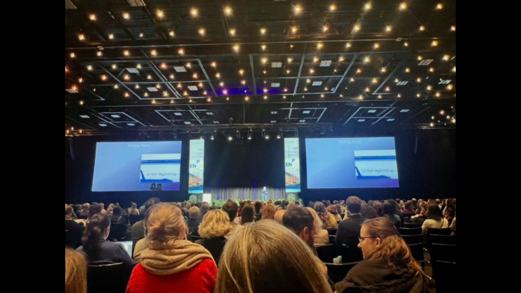 Huge audience watching Simon give a presentation in the far distance on a stage