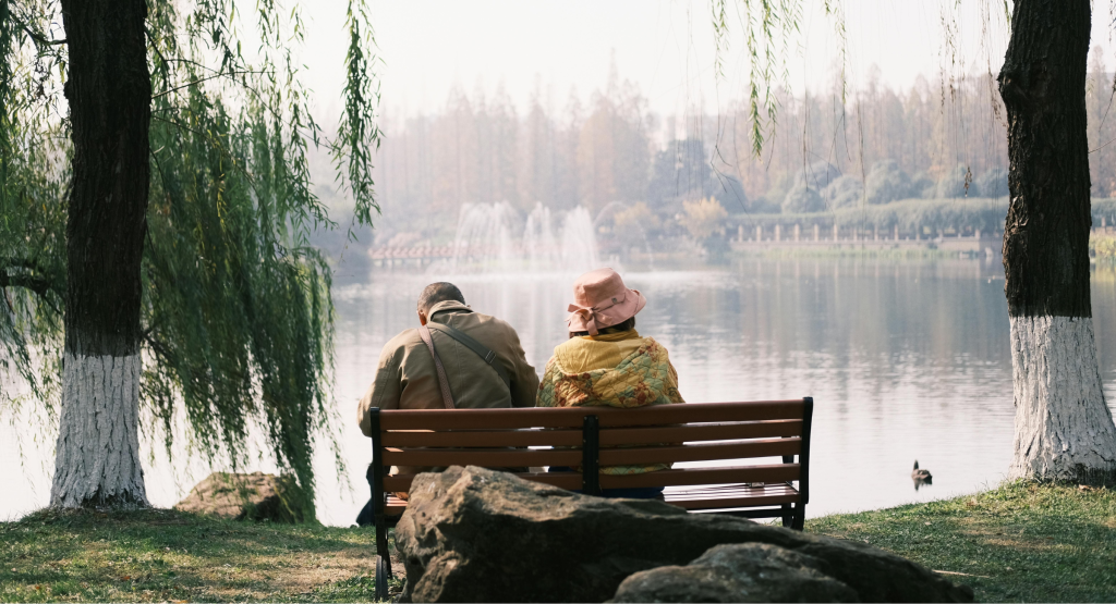 A couple sitting on a bench looking out at a lake
