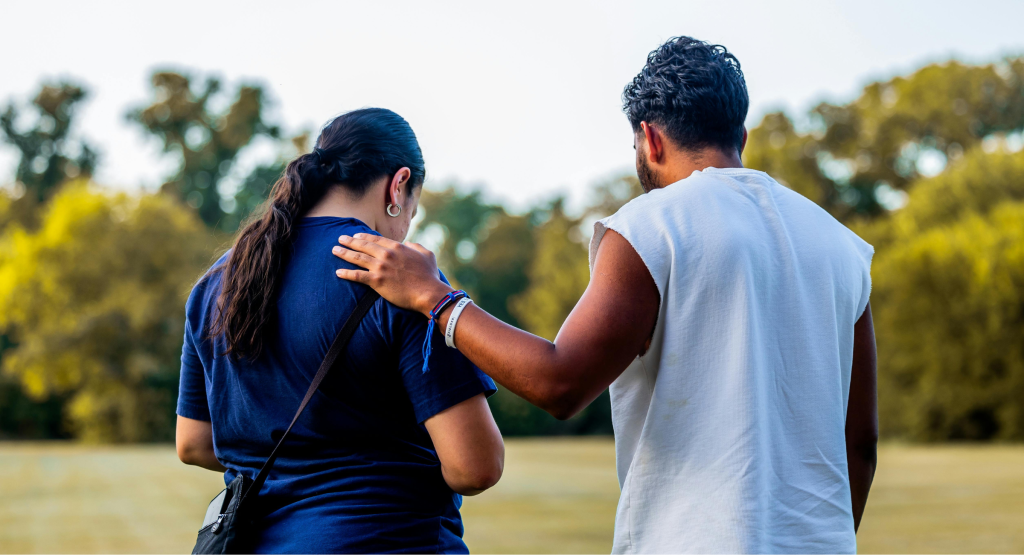 A man with his hand on a womans shoulder as a sign of support