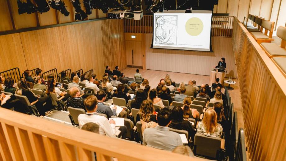 A photo of an auditorium with people watching a talk