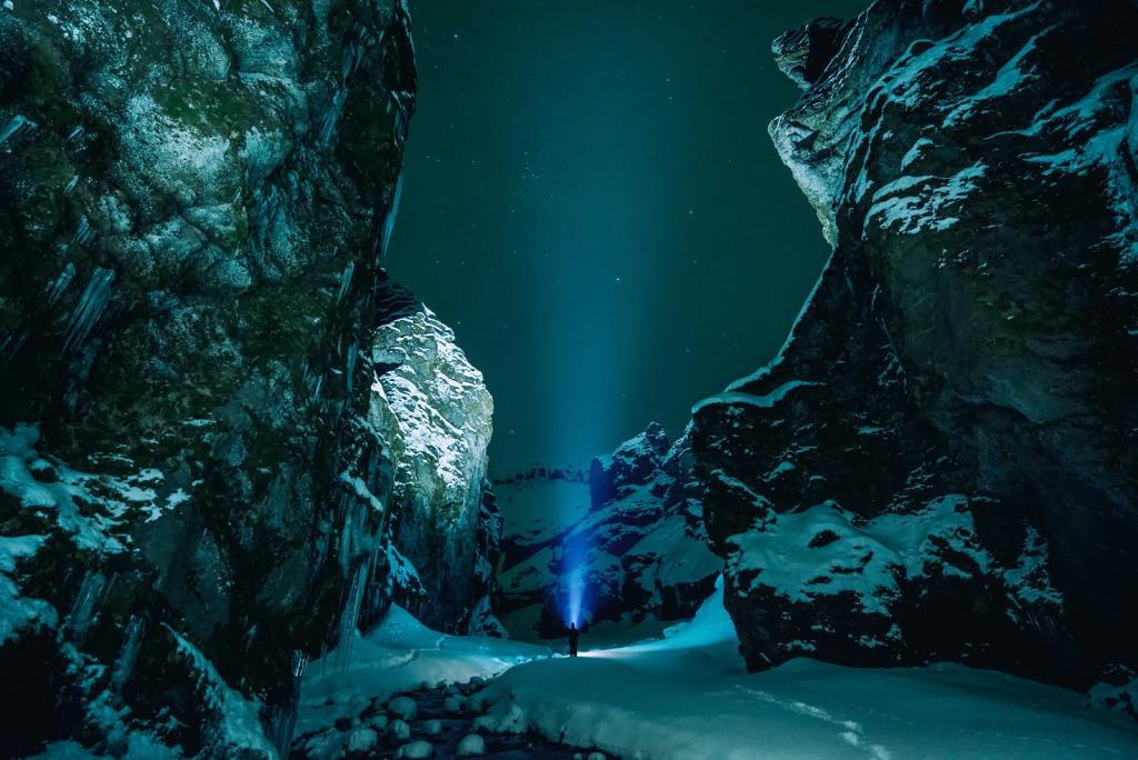 A figure with a torch in a dark, snowy ravine.