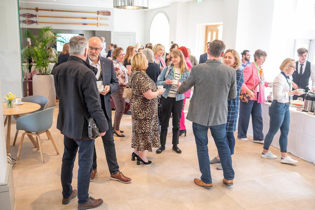 A group of people standing up & networking at King's College Cambridge