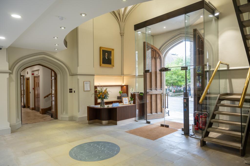 Refurbished reception area at Pitt Building, Cambridge. Glass doors opening up from the street into the foyer which is light and bright but retains an element of traditional Cambridge venue