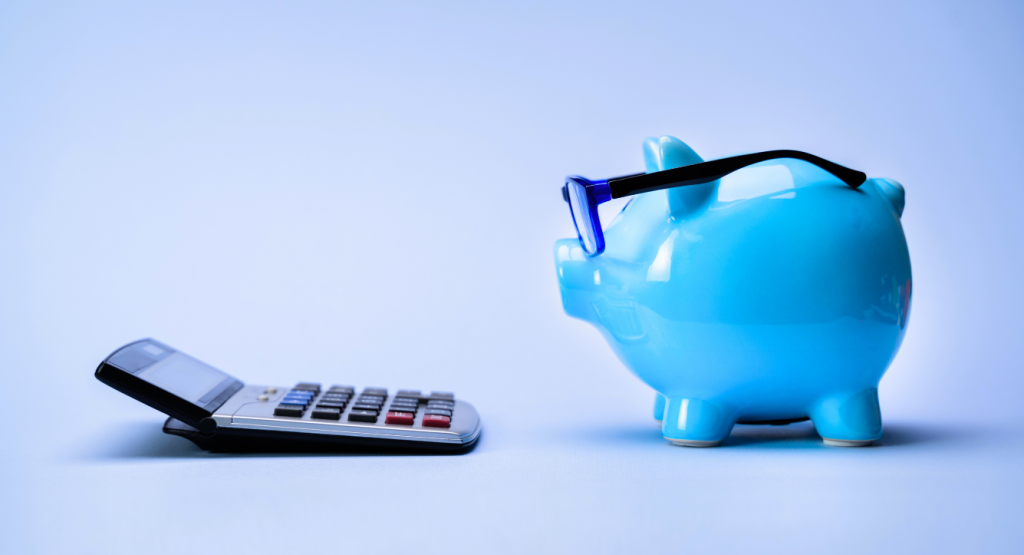 A blue piggy bank with glasses looking at a calculator