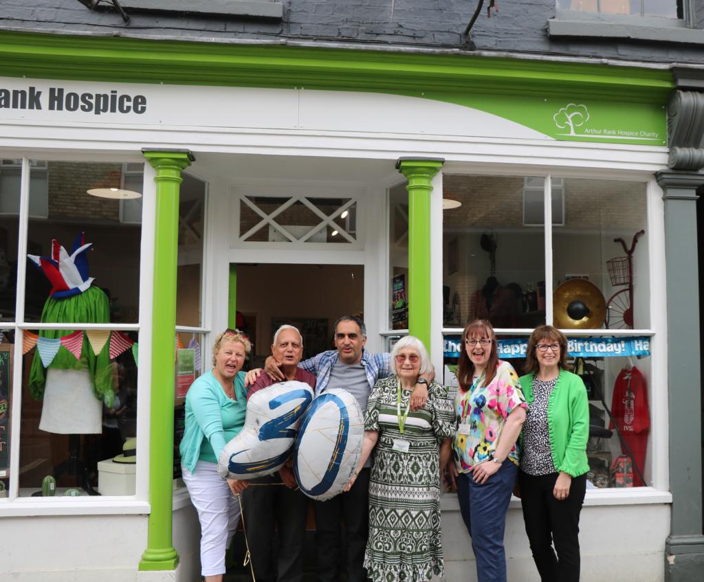Males and females outside a shop with a balloon