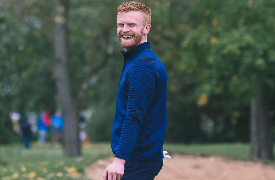 man stands smiling on golf course
