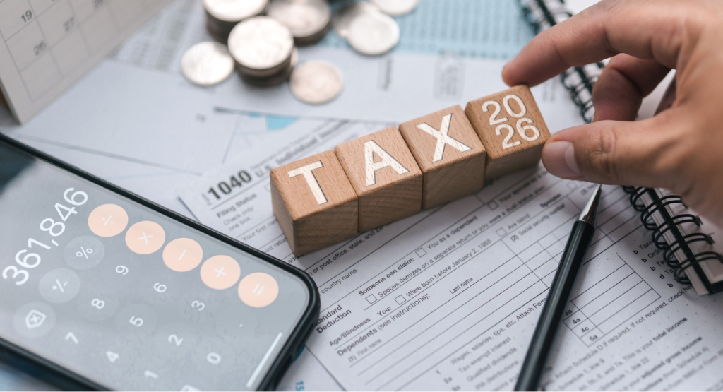 Letter blocks spelling out tax, with a calculator open on a phone