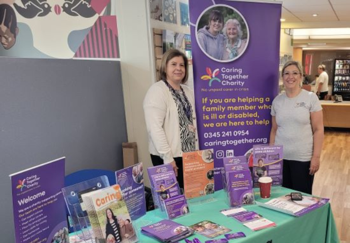 Two staff members with charity display stand