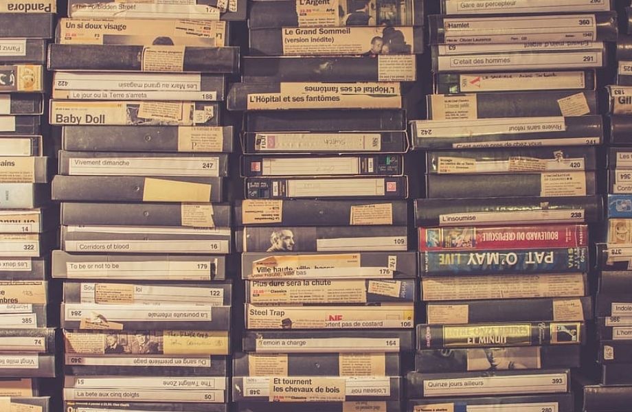 Stacked VHS tapes with handwritten labels, representing legacy media being preserved through digitisation.