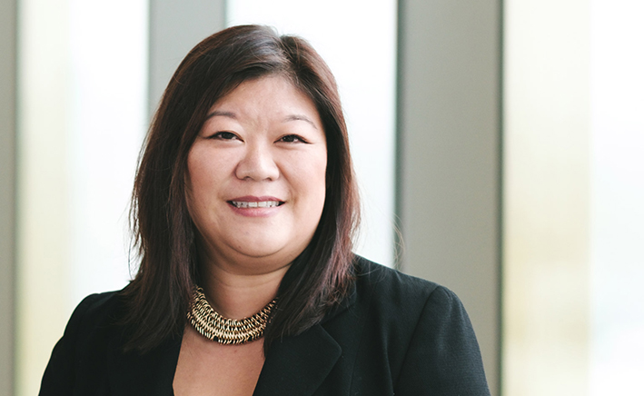Lady with dark hair in a black suit jacket with a necklace