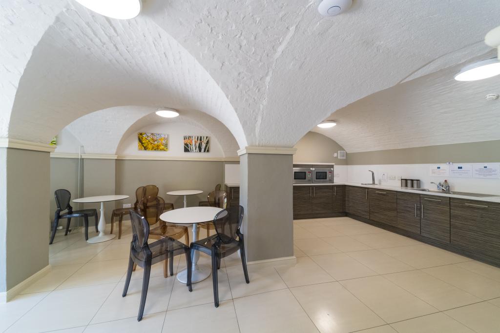 A bright spacious kitchen area with a table and chairs in the foreground