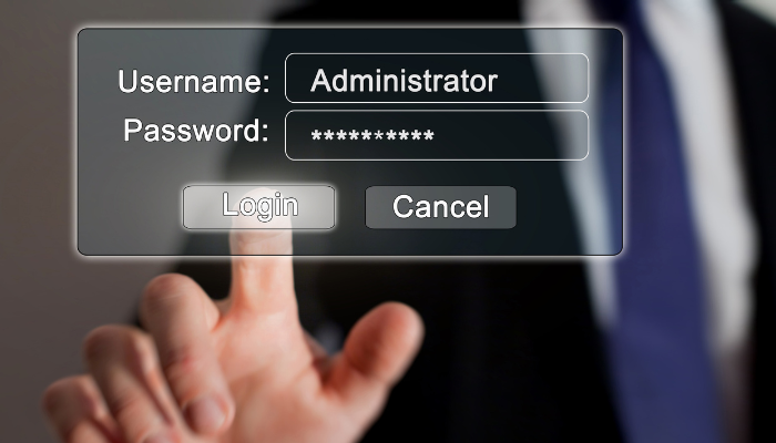 A hand with an outstretched finger pressing a button that says login on a computer screen, with the Username field completed as Administrator and the Password field starred out. 