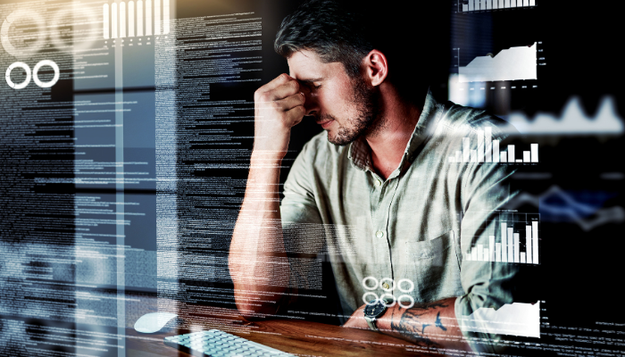 man with head in hands overwhelmed by lots of images of data around him