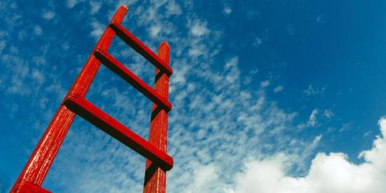 red ladder against a blue sky with clouds