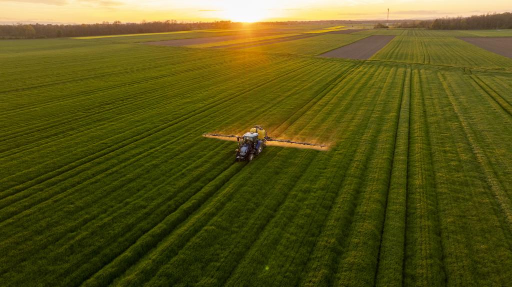 Tractor in a field with the sun setting in the distance 