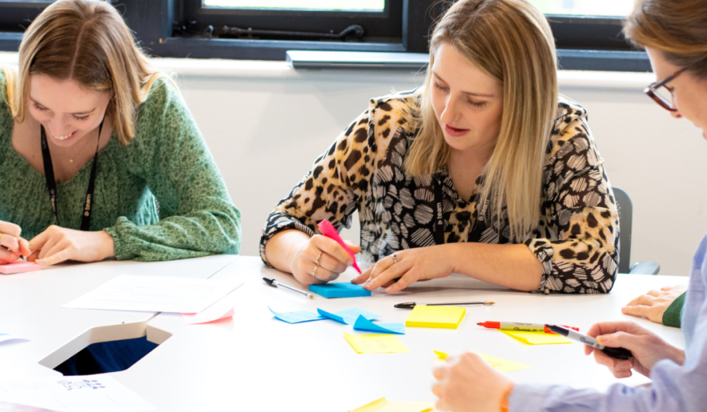 Three women outlining a FemTech Innovation strategy, collaborating, writing on post-its