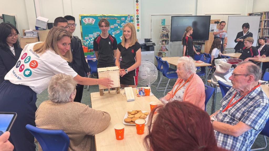 a group of students talking to elderly people