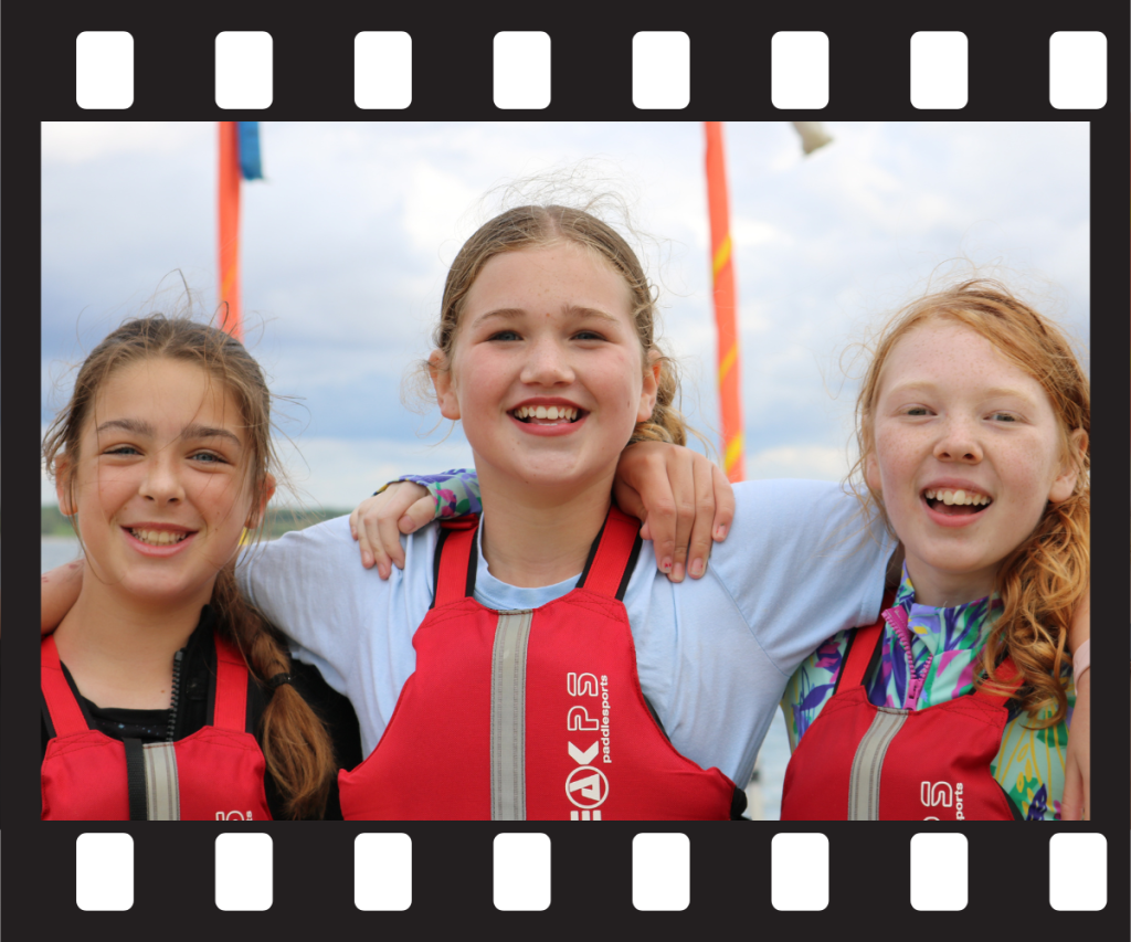 Three girls wearing lifejackets and smiling