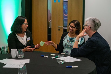people working together and helping eachother at a table with post it notes and paperwork