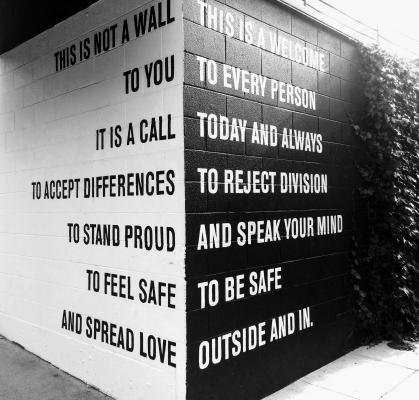 a white wall with the words it is a call to accept differences to stand proud to feel safe and a black wall with today and all ways, to reject division, and to speak your mind, to be safe