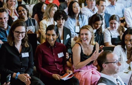 A group of people at a conference smiling and applauding.