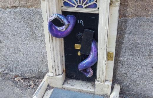 A miniature version of the door to 10 Downing Street, with purple tentacles emerging from it.