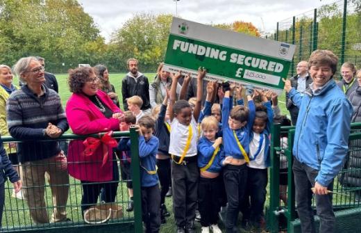 children holding a cheque on a sports field
