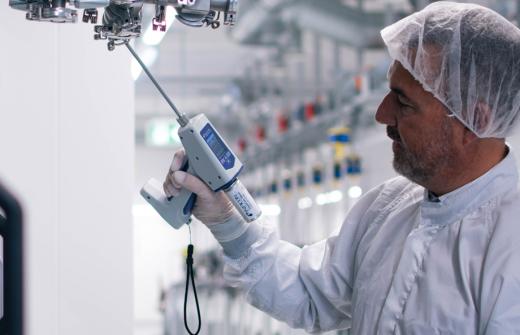 Test engineer using new SMART-Spray helium microdispenser for vacuum leak testing in a semiconductor fab.