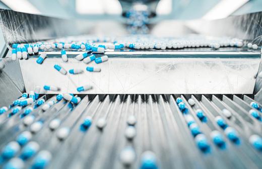 Filled pharmaceutical capsules moving along a production line. 