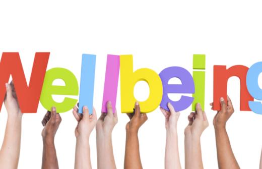 Hands holding up the multi coloured letters of the word 'wellbeing' 