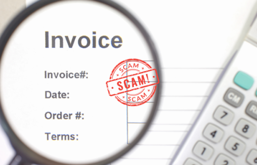 A picture of an accounting invoice, with a magnifying glass focussing in to scrutinise it and a calculator by its side. The invoice has been stamped with the word scam. 