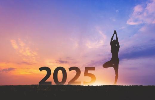 Sunrise and purple sky behind large 2025 numbers and a silhouette of a yoga pose