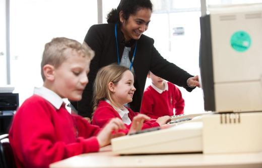 Children smile as a teacher points something out on a computer screen
