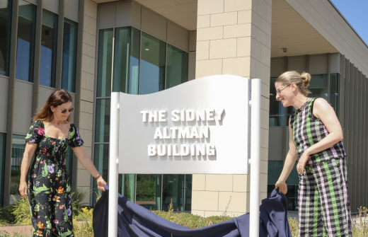 2 ladies in front of a sign the Sidney Altman Building at the Babraham Research Campus