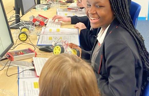 A girl smiles at her friend while around her children programme motorised buggies at the Centre for Computing History