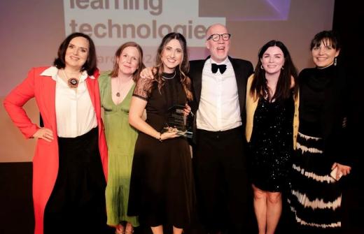 Simon on stage receiving an award, surrounded by team members