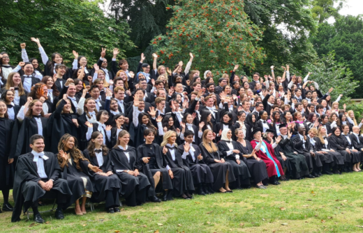 Group of postgraduates in College with hands in the air