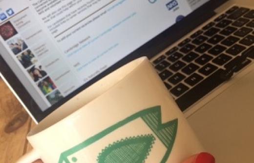 Claire's hand and mug with laptop inthe background