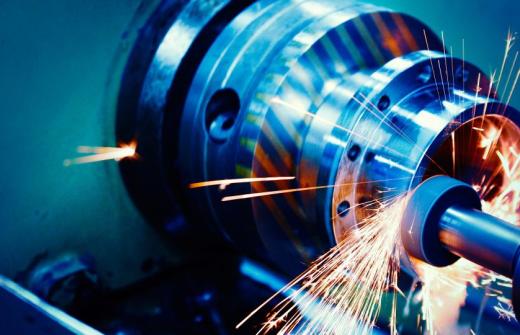 The image is washed in blue and hot white sparks fly off of a cylindrical saw as it comes into contact with metal.