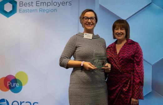 Two females holding a glass award, smiling at the camera 