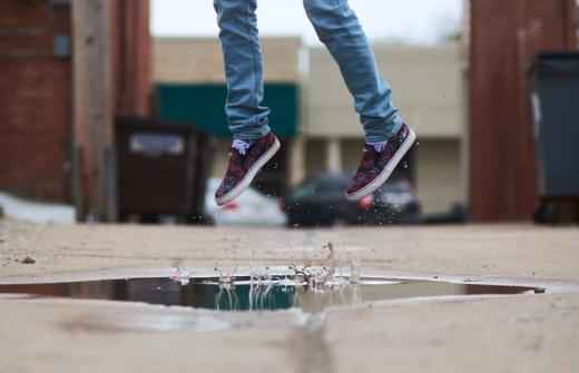 A pair of feet jumping from a puddle.