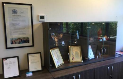 Queens Award Certificate on a wall next to trophy cabinet. Image courtesy of Global Inkjet Systems