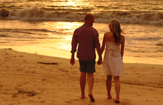 A couple walking on a beach at sunset